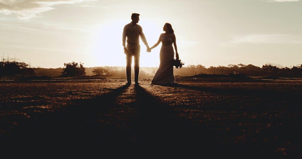 Newly married couple standing agains the sunset